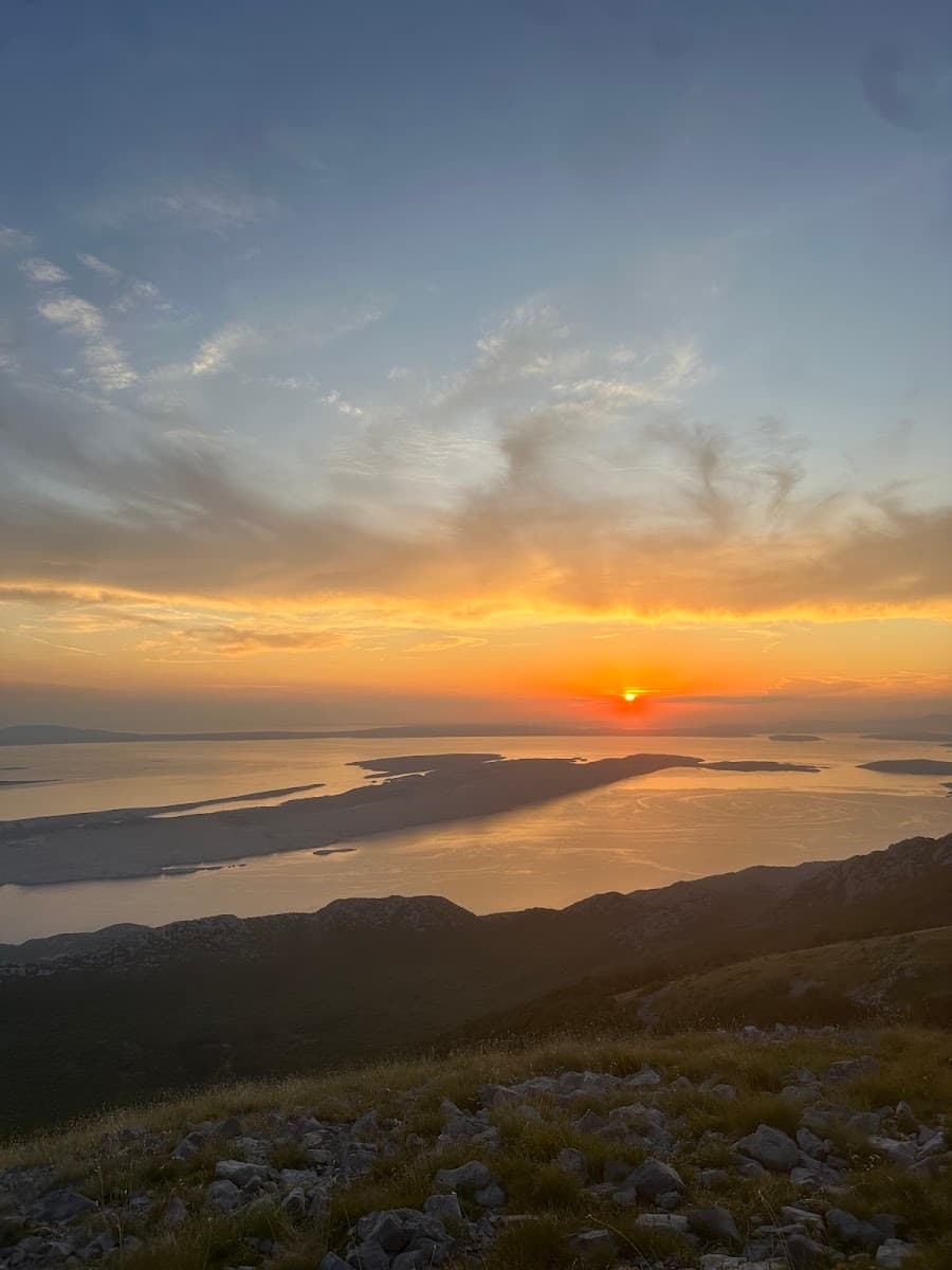 Mountain overlook at sunset above islands and calm sea water with golden light