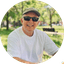 Person wearing a cap and sunglasses outdoors in a park