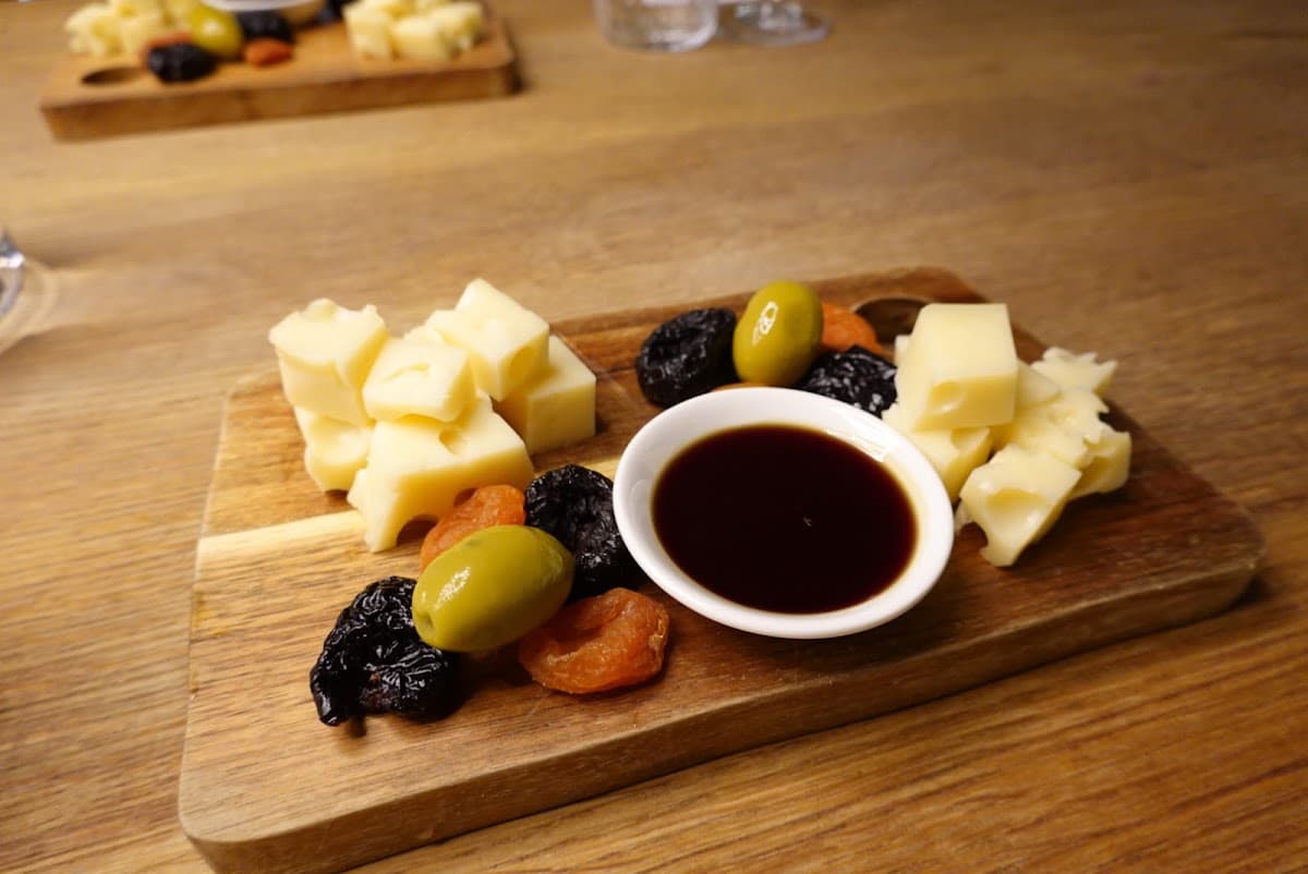 Cheese and snack board with cubed cheese, olives, dried fruit, and dipping sauce